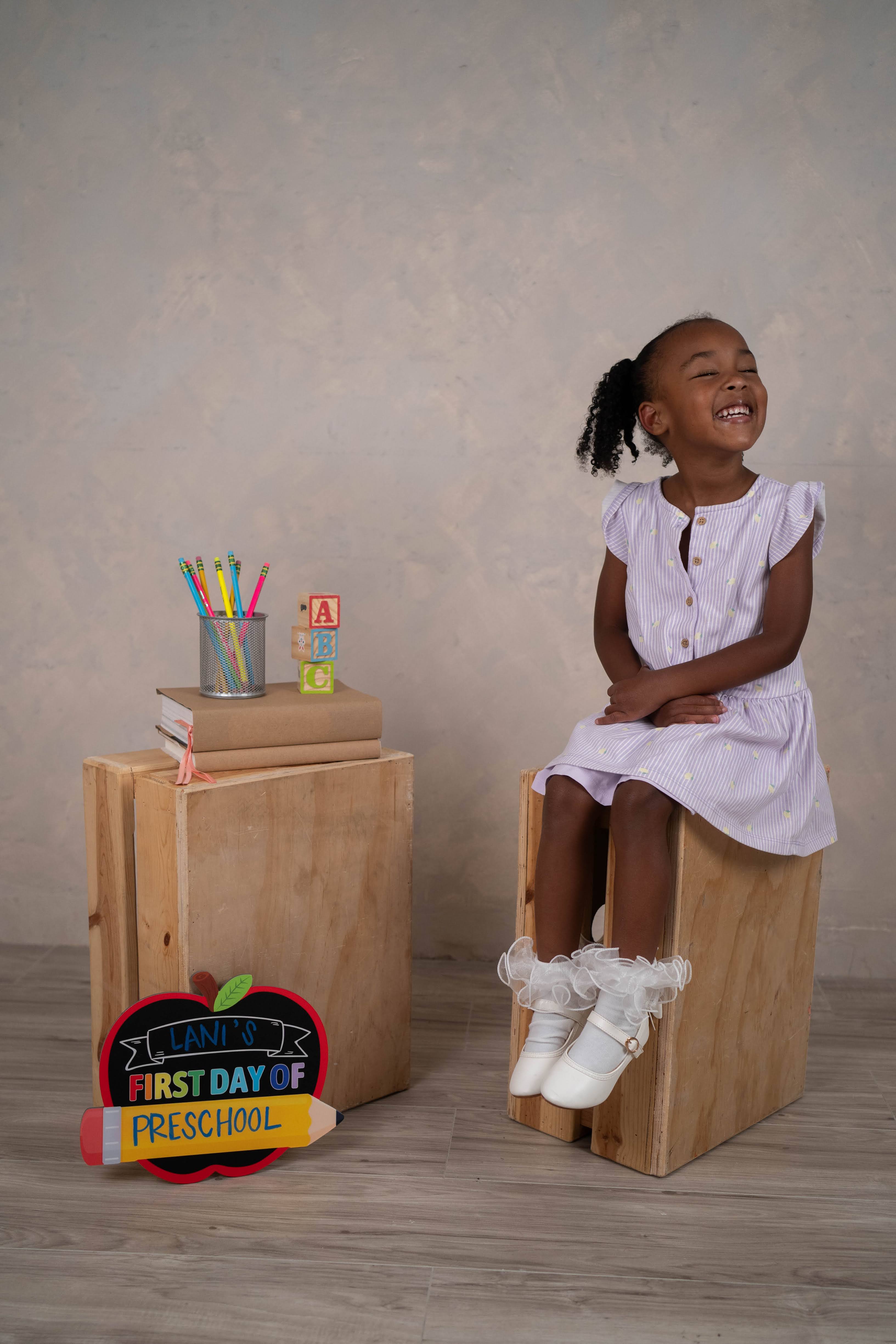Back-to-school mini portrait with a child posing beside school props.